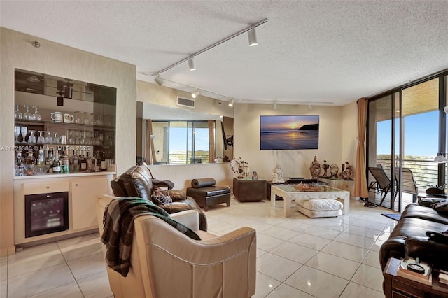 living room with bar, floor to ceiling windows, a textured ceiling, and light tile patterned floors