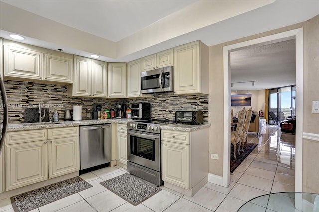 kitchen with light tile patterned flooring, stainless steel appliances, sink, and cream cabinetry