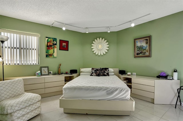 bedroom featuring rail lighting and a textured ceiling