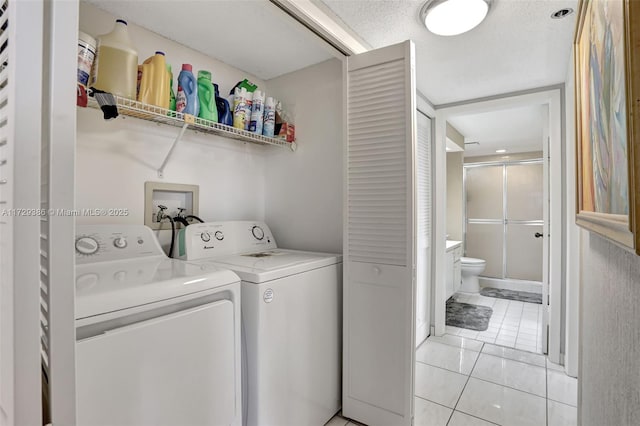 washroom featuring light tile patterned flooring, separate washer and dryer, and a textured ceiling