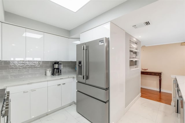 kitchen featuring white cabinetry, light stone countertops, and high end refrigerator