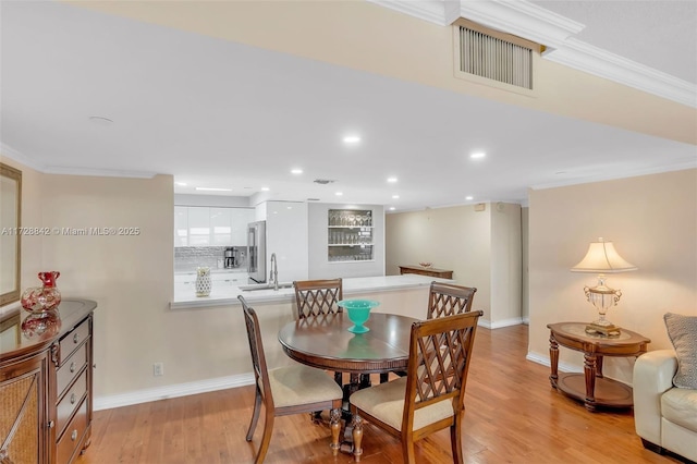 dining room featuring ornamental molding, sink, and light wood-type flooring