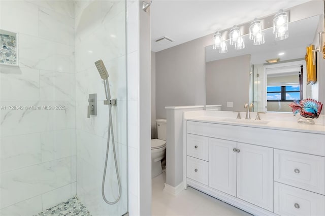 bathroom featuring vanity, tiled shower, and toilet