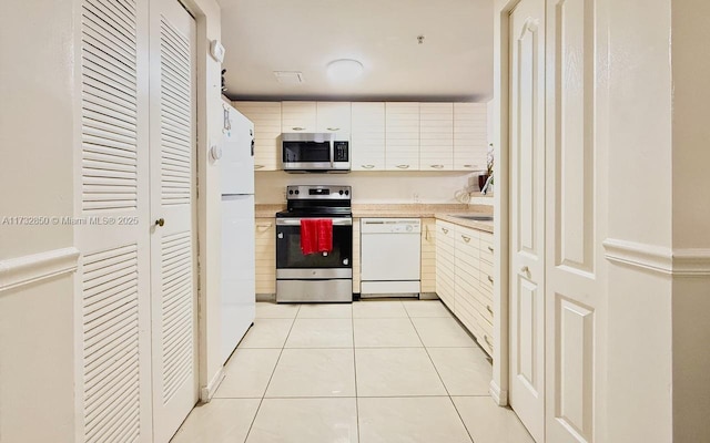 kitchen featuring light tile patterned flooring, white cabinetry, and appliances with stainless steel finishes