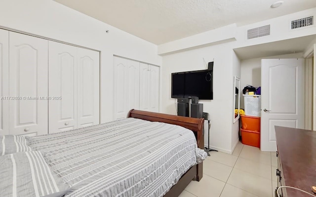 tiled bedroom featuring multiple closets