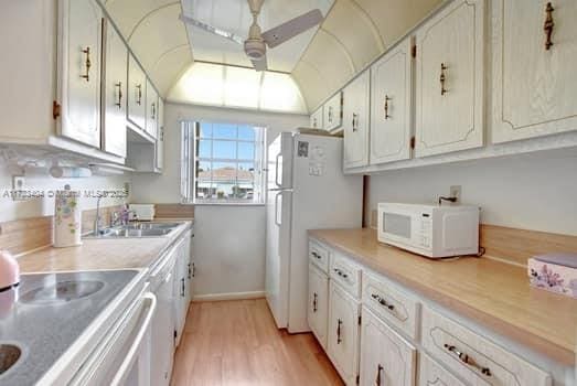 kitchen with sink, white appliances, ceiling fan, white cabinetry, and light hardwood / wood-style floors