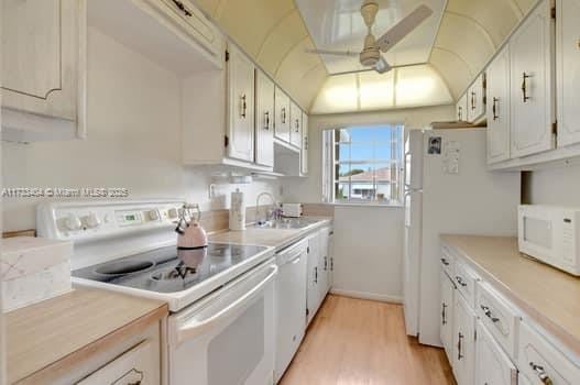 kitchen with sink, white cabinets, ceiling fan, white appliances, and light hardwood / wood-style flooring