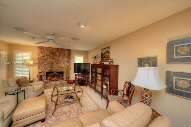 living room featuring a stone fireplace and ceiling fan