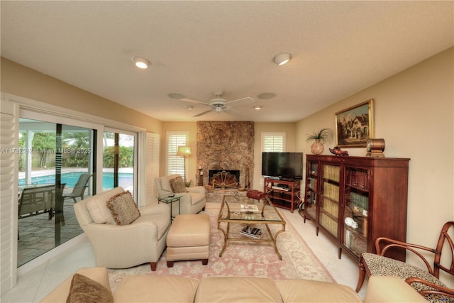 tiled living room with ceiling fan and a fireplace