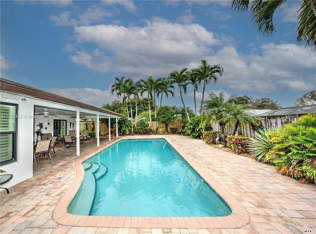 view of swimming pool with ceiling fan and a patio