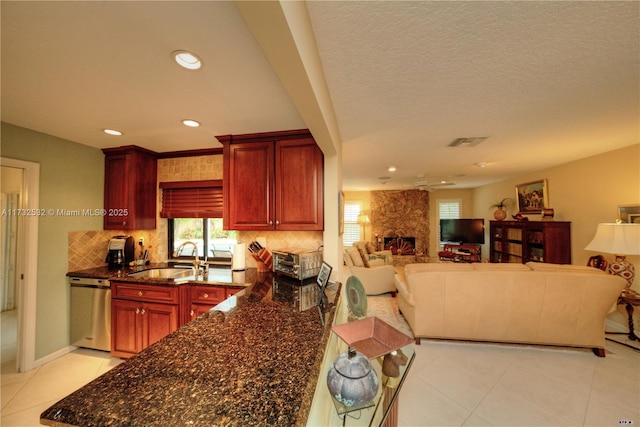 kitchen with dark stone counters, dishwasher, sink, and backsplash