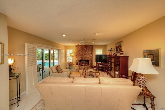 tiled living room with ceiling fan and a fireplace