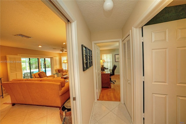 hall featuring a textured ceiling and light tile patterned floors