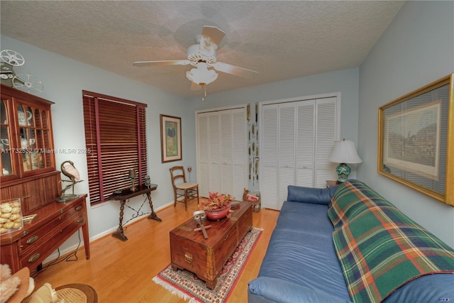 living room featuring hardwood / wood-style flooring, ceiling fan, and a textured ceiling