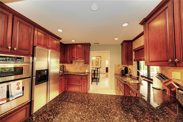 kitchen featuring light tile patterned flooring, sink, dark stone countertops, decorative backsplash, and stainless steel appliances