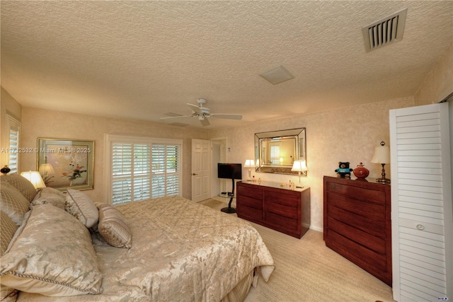 bedroom featuring light carpet, ceiling fan, and a textured ceiling