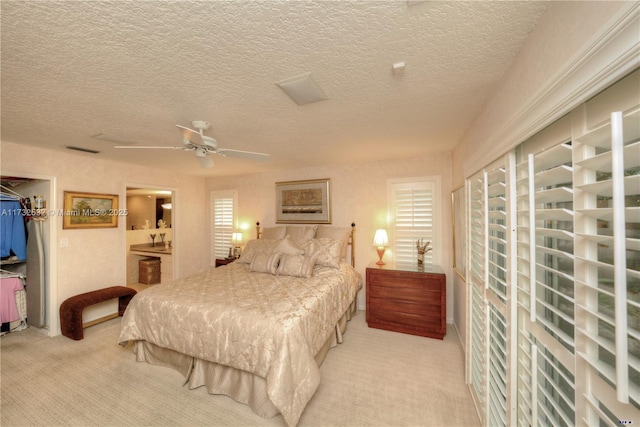 carpeted bedroom with ceiling fan, a walk in closet, a textured ceiling, and a closet