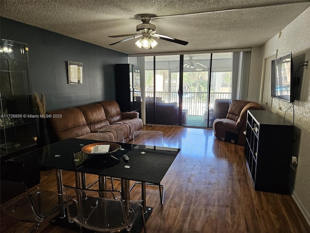 living room featuring dark wood-type flooring, ceiling fan, and a textured ceiling