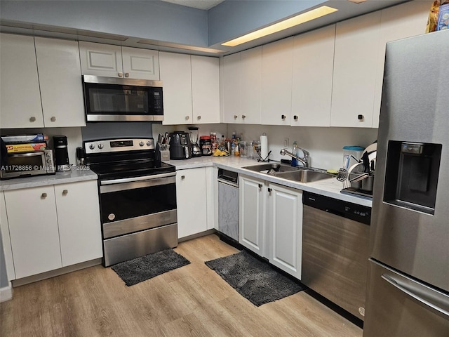 kitchen with sink, stainless steel appliances, light hardwood / wood-style floors, and white cabinets