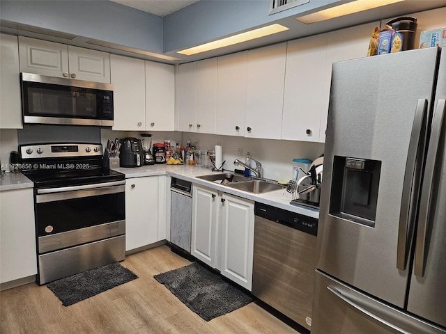 kitchen with white cabinetry, sink, stainless steel appliances, and light hardwood / wood-style floors