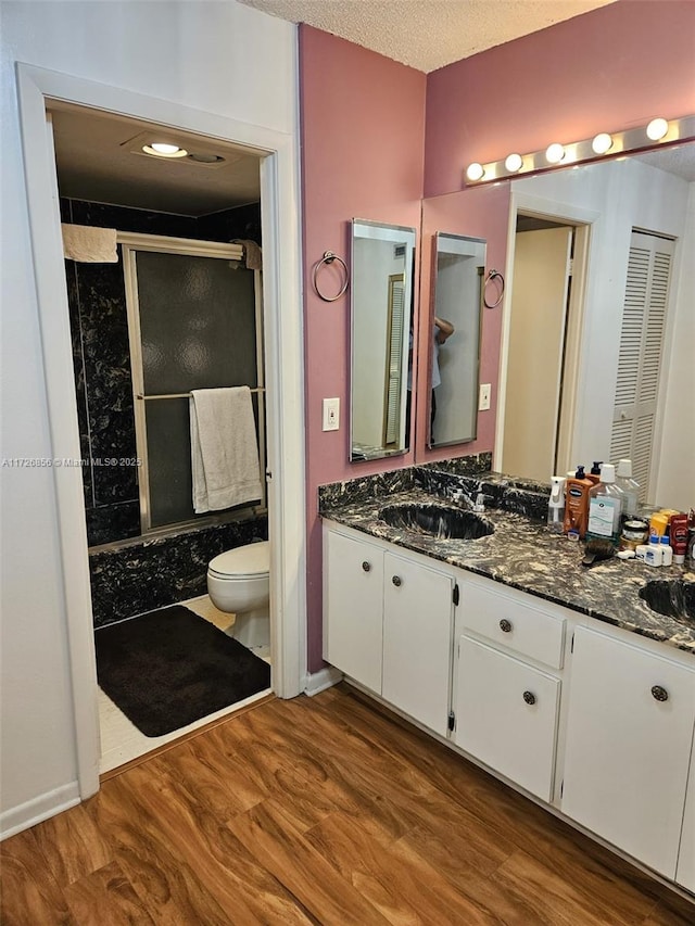 bathroom featuring toilet, an enclosed shower, wood-type flooring, a textured ceiling, and vanity