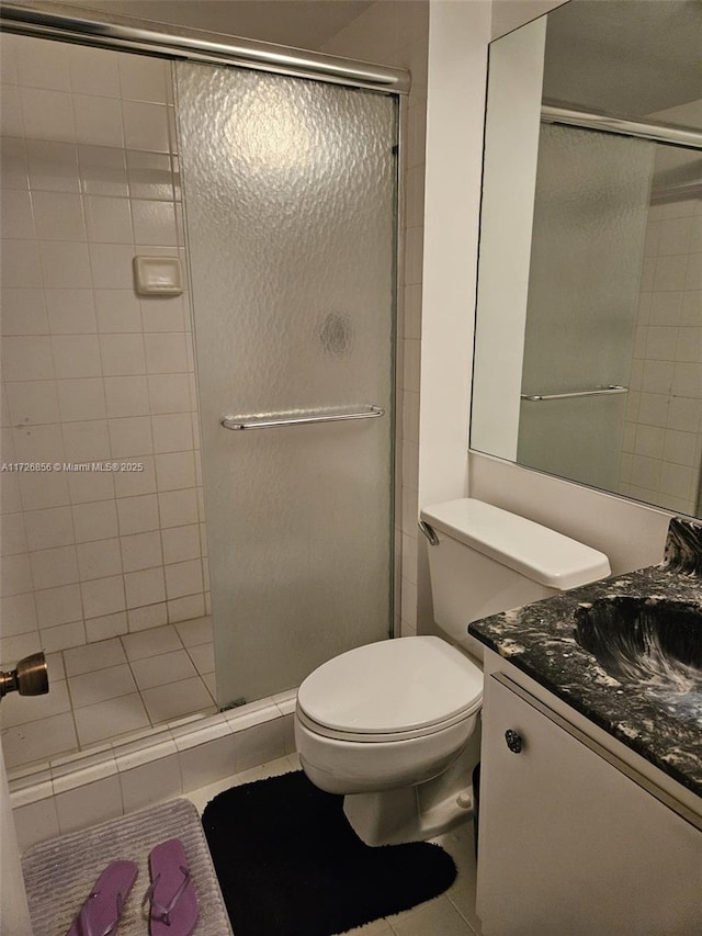 bathroom with toilet, vanity, tile patterned floors, and a shower with shower door