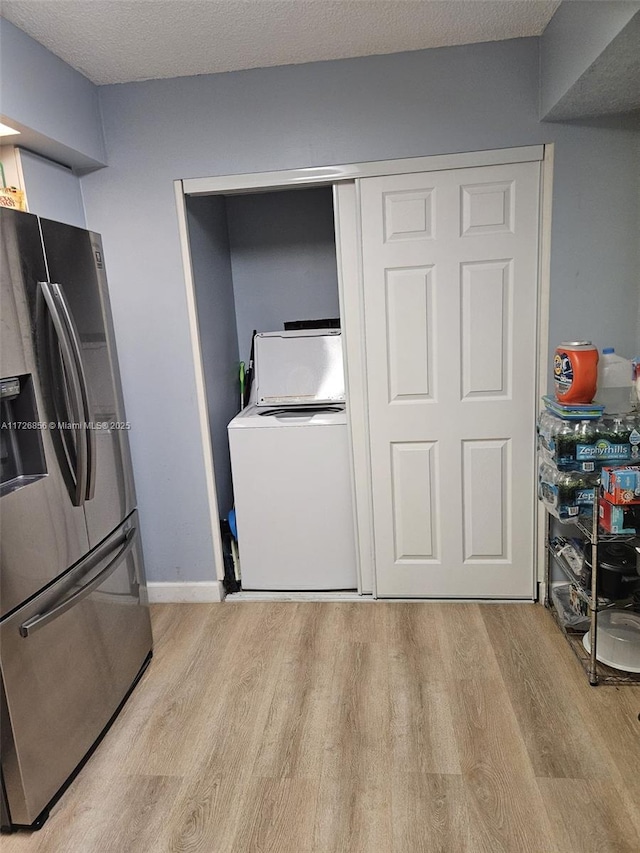 kitchen with washer / clothes dryer, stainless steel refrigerator with ice dispenser, a textured ceiling, and light hardwood / wood-style flooring