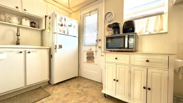 kitchen featuring white refrigerator, white cabinetry, and sink