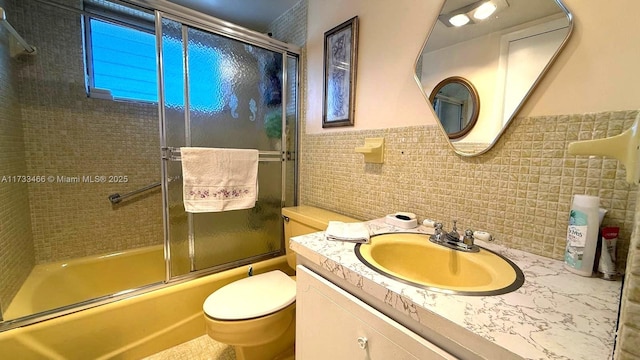 full bathroom featuring enclosed tub / shower combo, tile walls, vanity, and toilet