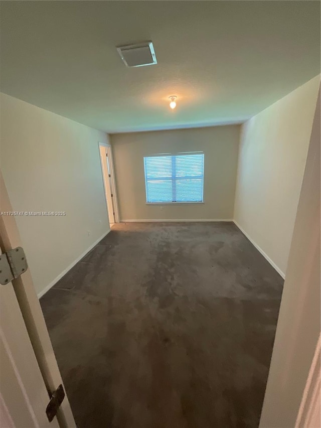 spare room with baseboards and dark colored carpet