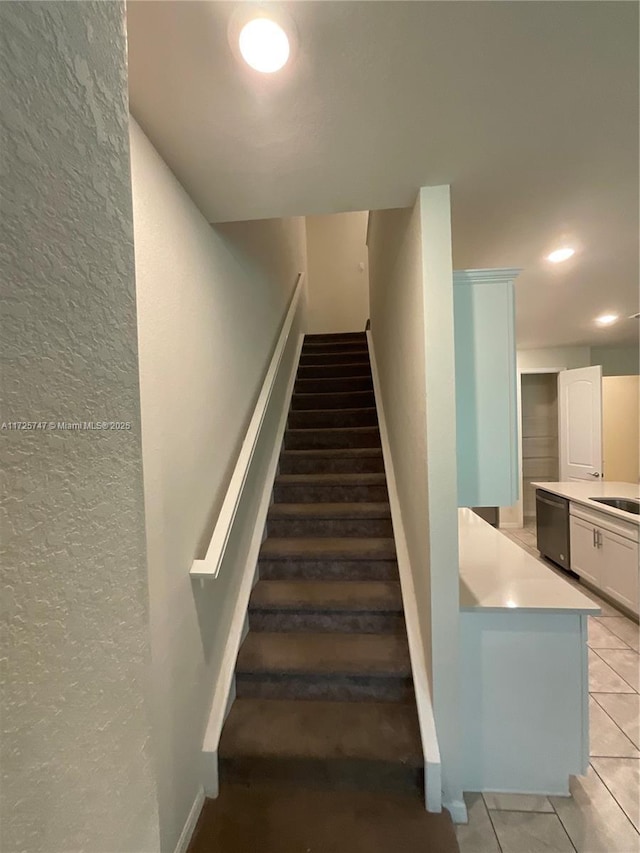 staircase featuring a textured wall, baseboards, recessed lighting, and tile patterned flooring