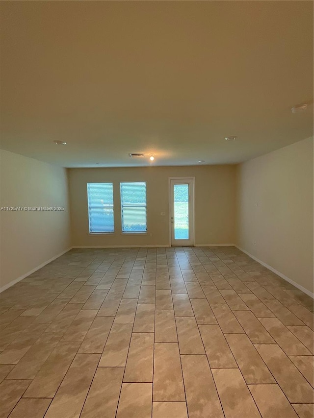 empty room featuring light tile patterned flooring and baseboards