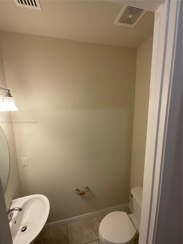 bathroom featuring tile patterned floors, visible vents, toilet, a sink, and baseboards