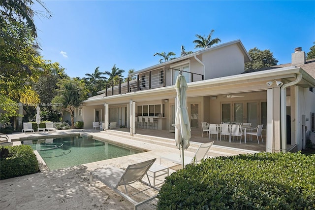 rear view of house with ceiling fan, a balcony, and a patio