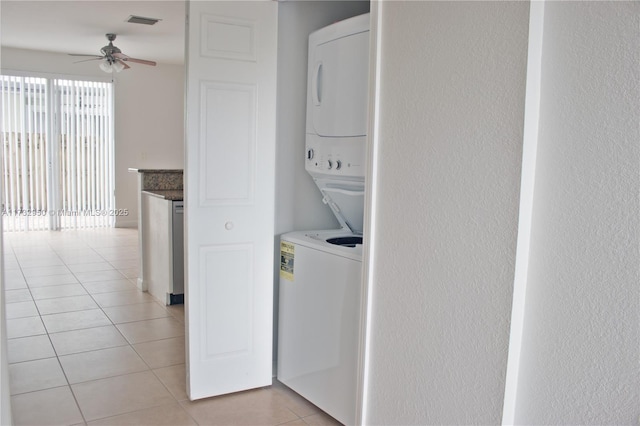 laundry area with stacked washer and dryer, light tile patterned floors, and ceiling fan