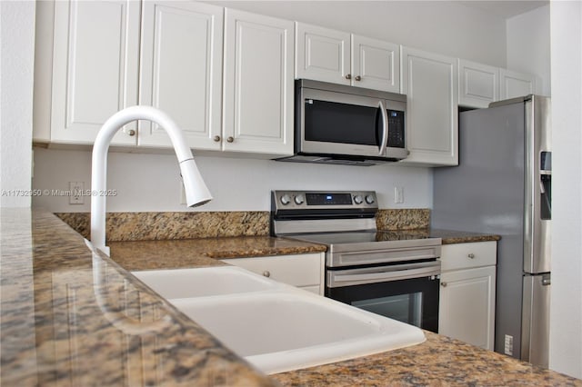 kitchen featuring stainless steel appliances, dark stone counters, and white cabinets