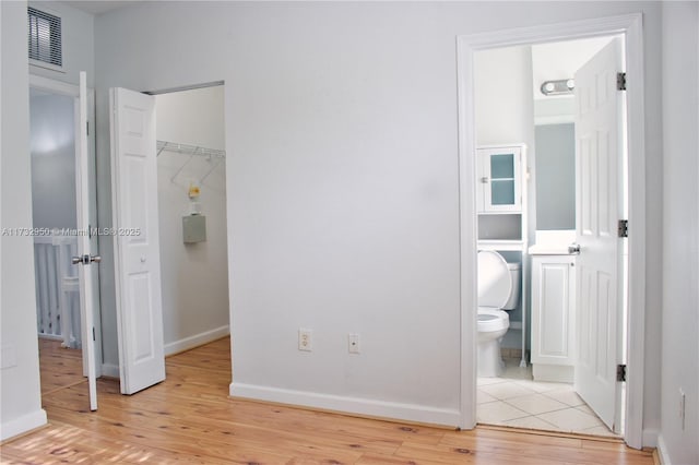 unfurnished bedroom featuring a walk in closet, connected bathroom, light hardwood / wood-style floors, and a closet