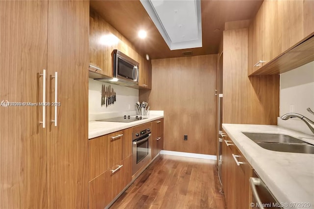 kitchen featuring brown cabinets, light wood-style flooring, appliances with stainless steel finishes, a sink, and modern cabinets