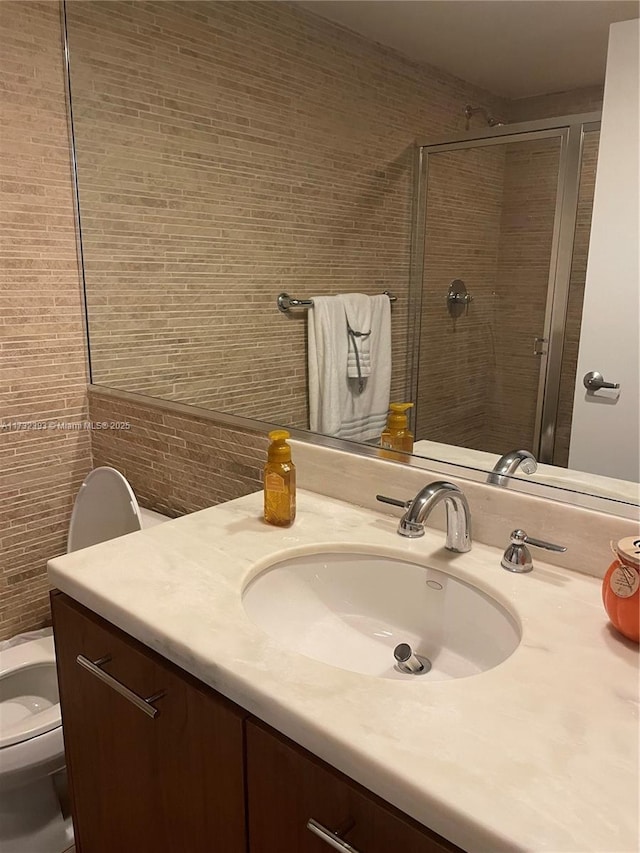 full bathroom featuring a stall shower, tile walls, vanity, and toilet