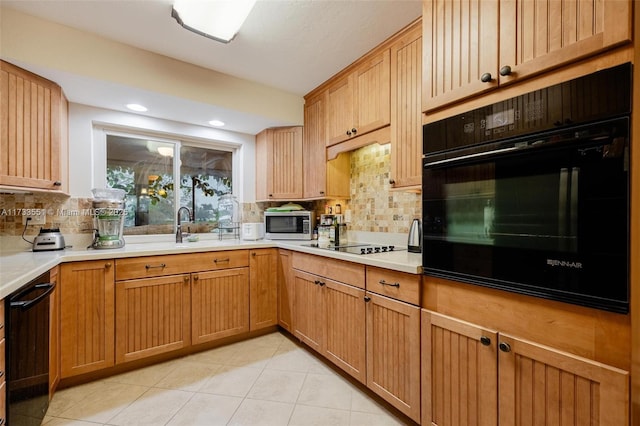 kitchen featuring tasteful backsplash, sink, light tile patterned floors, and black appliances