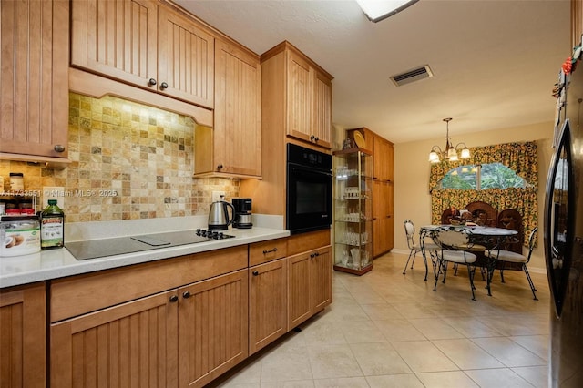 kitchen featuring an inviting chandelier, hanging light fixtures, light tile patterned floors, decorative backsplash, and black appliances