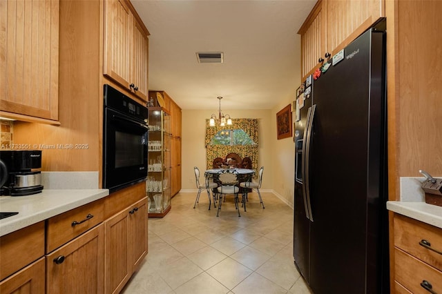 kitchen with hanging light fixtures, light tile patterned floors, black appliances, and a chandelier