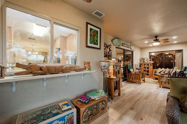 interior space with ceiling fan with notable chandelier and light hardwood / wood-style flooring