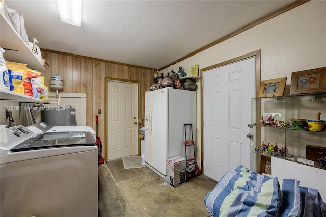 laundry room featuring wood walls, crown molding, a textured ceiling, washing machine and dryer, and water heater