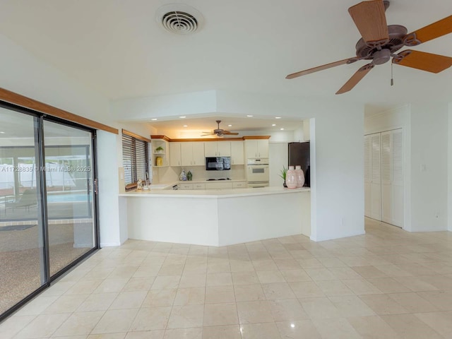 kitchen with white cabinetry, refrigerator, and kitchen peninsula