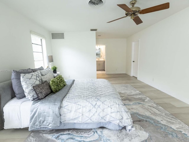 bedroom with ceiling fan, ensuite bathroom, and light hardwood / wood-style floors