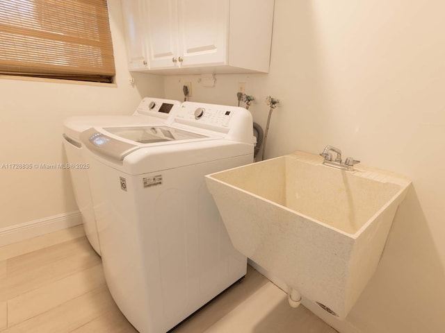 clothes washing area with cabinets, sink, and washer and dryer