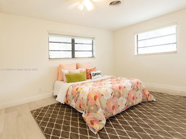 bedroom with multiple windows, hardwood / wood-style floors, and ceiling fan