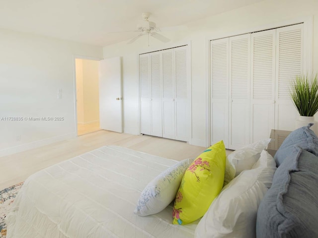 bedroom with multiple closets, ceiling fan, and light hardwood / wood-style flooring