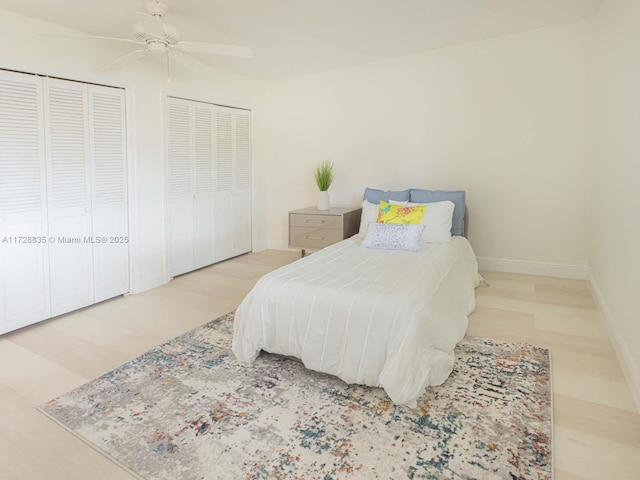 bedroom featuring hardwood / wood-style floors, two closets, and ceiling fan